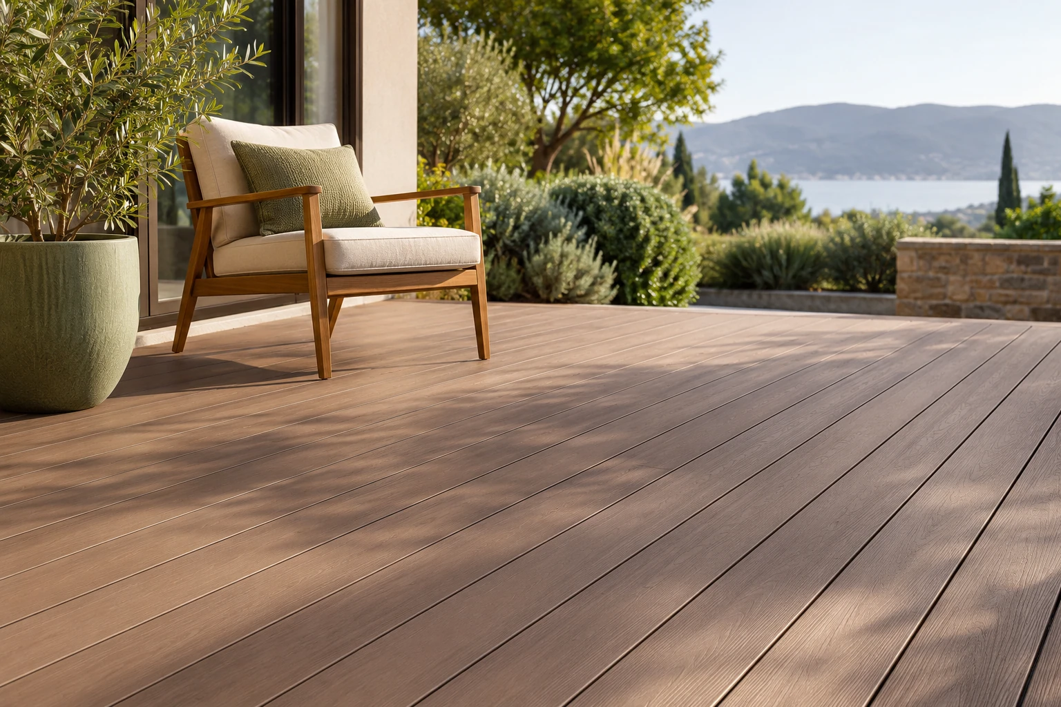 Fauteuil en bois et coussin sur terrasse en bois composite, vue jardin et mer